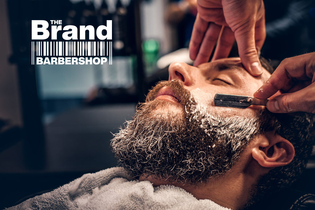 Close up image of barber shaving a man with a sharp steel razor.